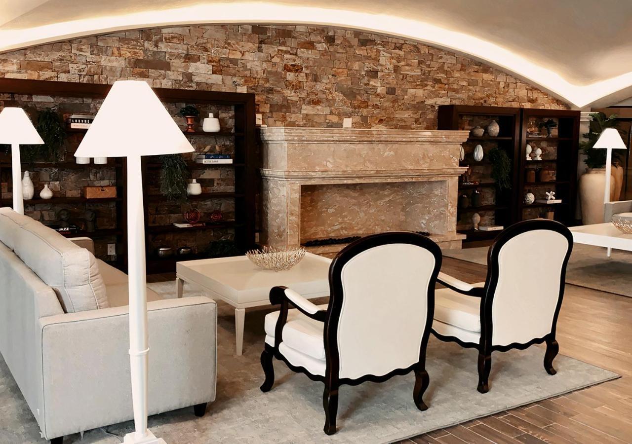 Buona Vitta Gramado Resort & Spa By Gramado Parks Экстерьер фото The photo shows a stylish living room with a modern design. In the center, there is a light-colored sofa and two elegant white armchairs with black wooden frames. A coffee table is placed in front of the sofa. Behind them, there is a large, decorativ