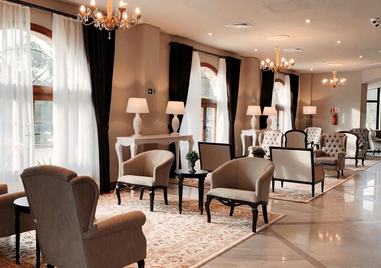 Buona Vitta Gramado Resort & Spa By Gramado Parks Экстерьер фото The photo depicts a stylish and sophisticated lounge area. It features several elegant chairs and sofas, arranged around small tables on a decorative rug. The room is well-lit with natural light coming in through large windows dressed with flowing wh