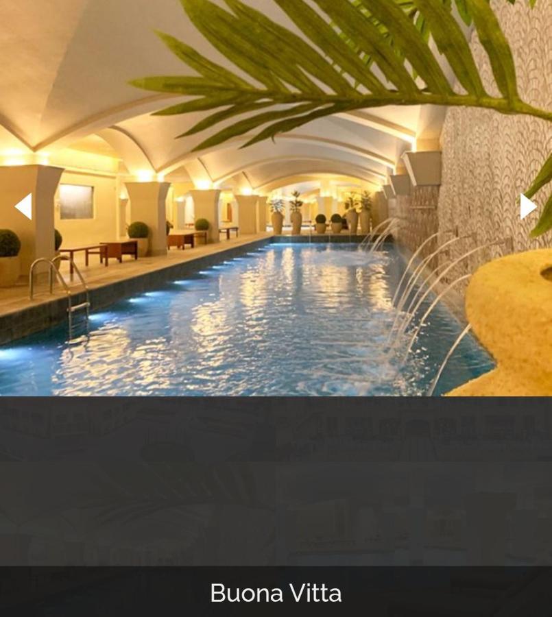 Buona Vitta Gramado Resort & Spa By Gramado Parks Экстерьер фото The photo depicts an elegant indoor swimming pool area. The pool is illuminated with lights along its edge, and there are gentle water features creating a calming atmosphere. The ceiling has an arched design, and the space is decorated with plants an
