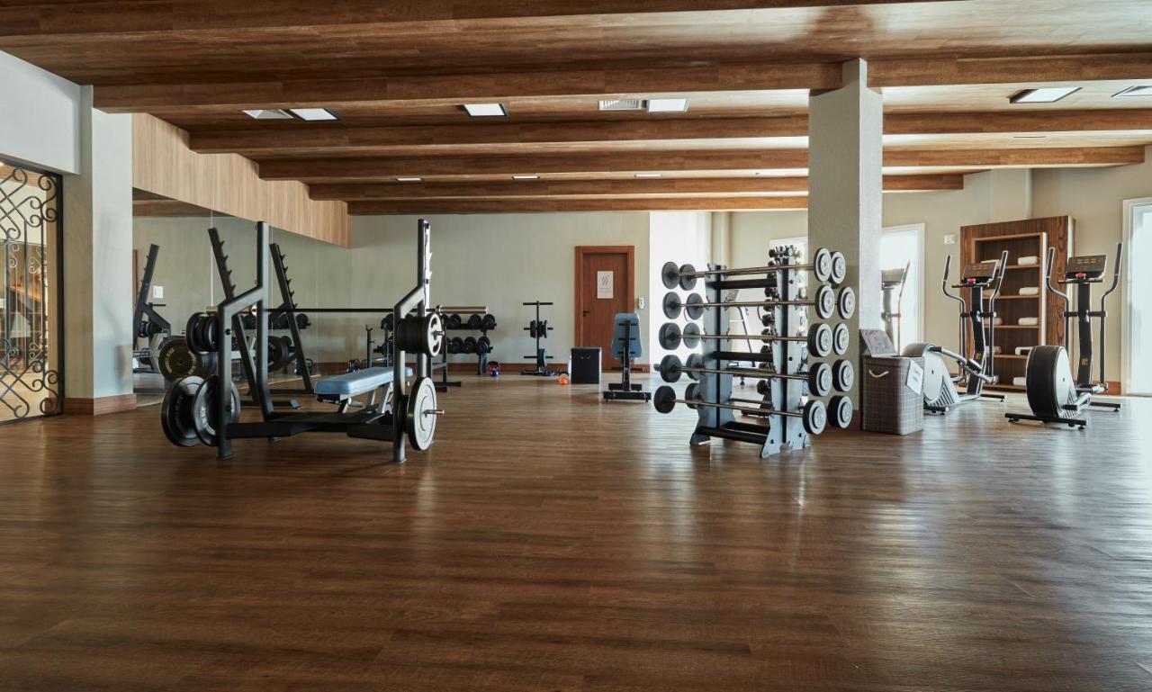 Buona Vitta Gramado Resort & Spa By Gramado Parks Экстерьер фото The photo shows a spacious gym with a wooden floor and wooden ceiling beams. Various pieces of gym equipment are visible, including weight benches and racks with weights. On one side, there are free weights organized on a rack, while other equipment 