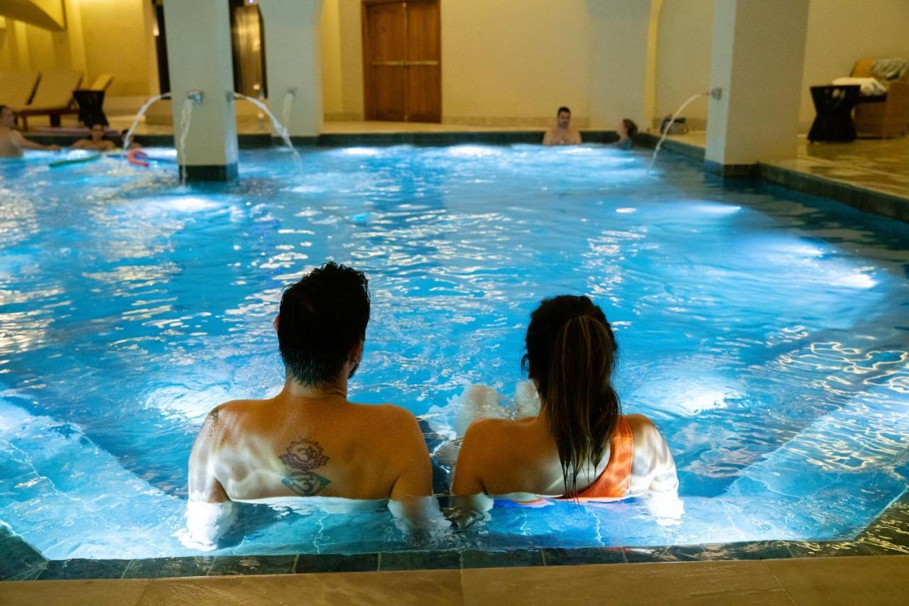 Buona Vitta Gramado Resort & Spa By Gramado Parks Экстерьер фото The photo shows a couple sitting in a swimming pool with gentle lighting. They are facing away from the camera, appearing relaxed and enjoying their time together. The water is illuminated with a soft blue light, creating a serene atmosphere. In the 
