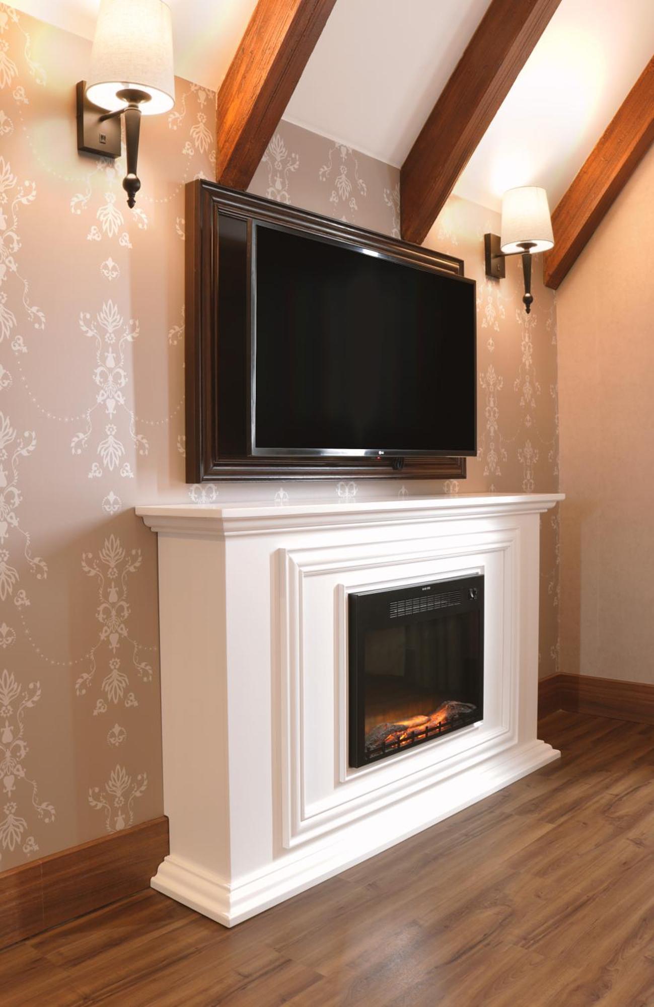Buona Vitta Gramado Resort & Spa By Gramado Parks Экстерьер фото The image shows a modern living room setup featuring a white mantel with an electric fireplace. Above the mantel, there is a large flat-screen television mounted on the wall. The fireplace has a glass front and displays a realistic flame effect, crea