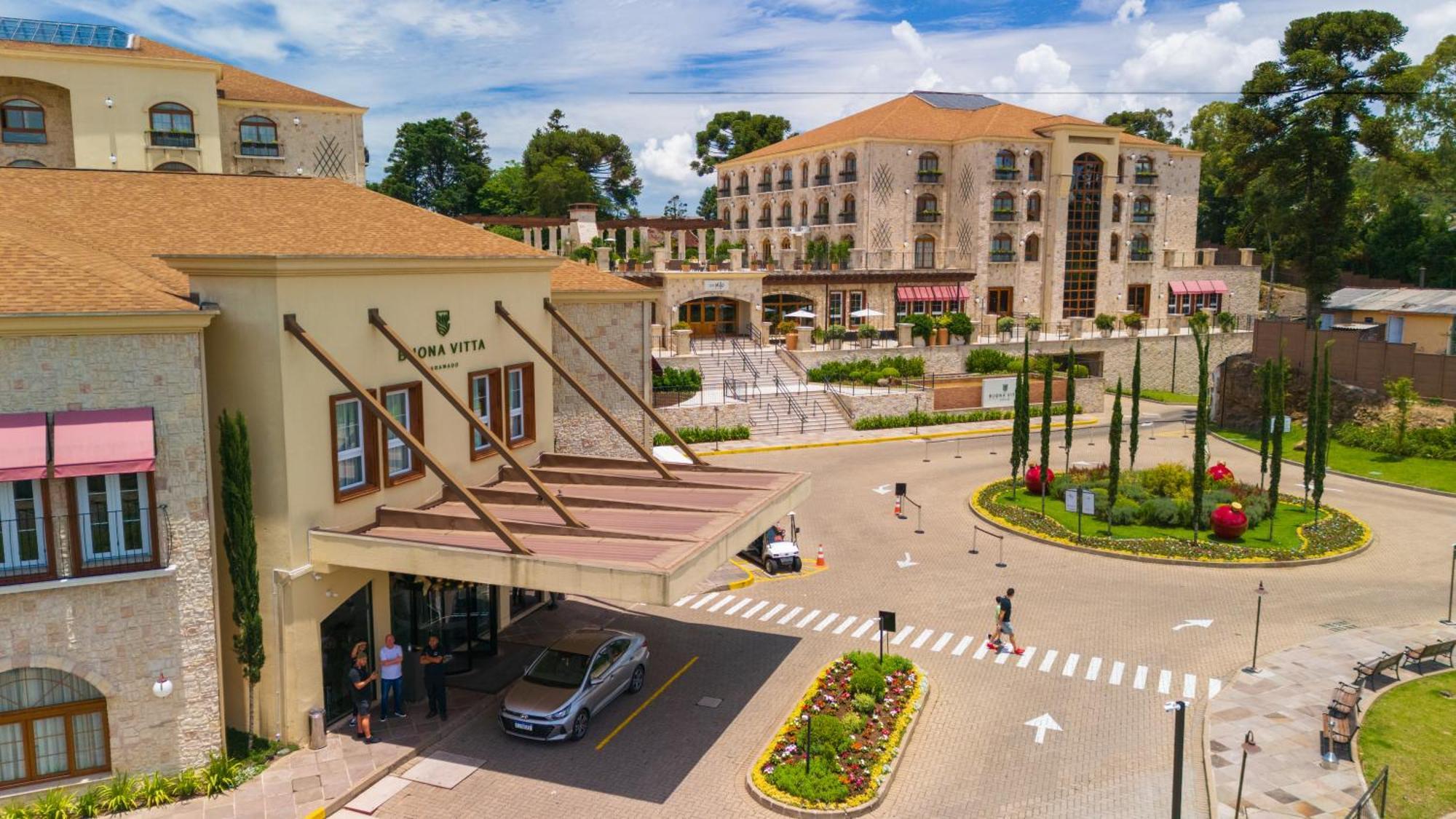 Buona Vitta Gramado Resort & Spa By Gramado Parks Экстерьер фото The photo shows a luxurious hotel or resort entrance, featuring a modern yet elegant architectural design. In the foreground, there is a covered entrance where vehicles are likely dropping off guests. The building has a stone facade and a welcoming e