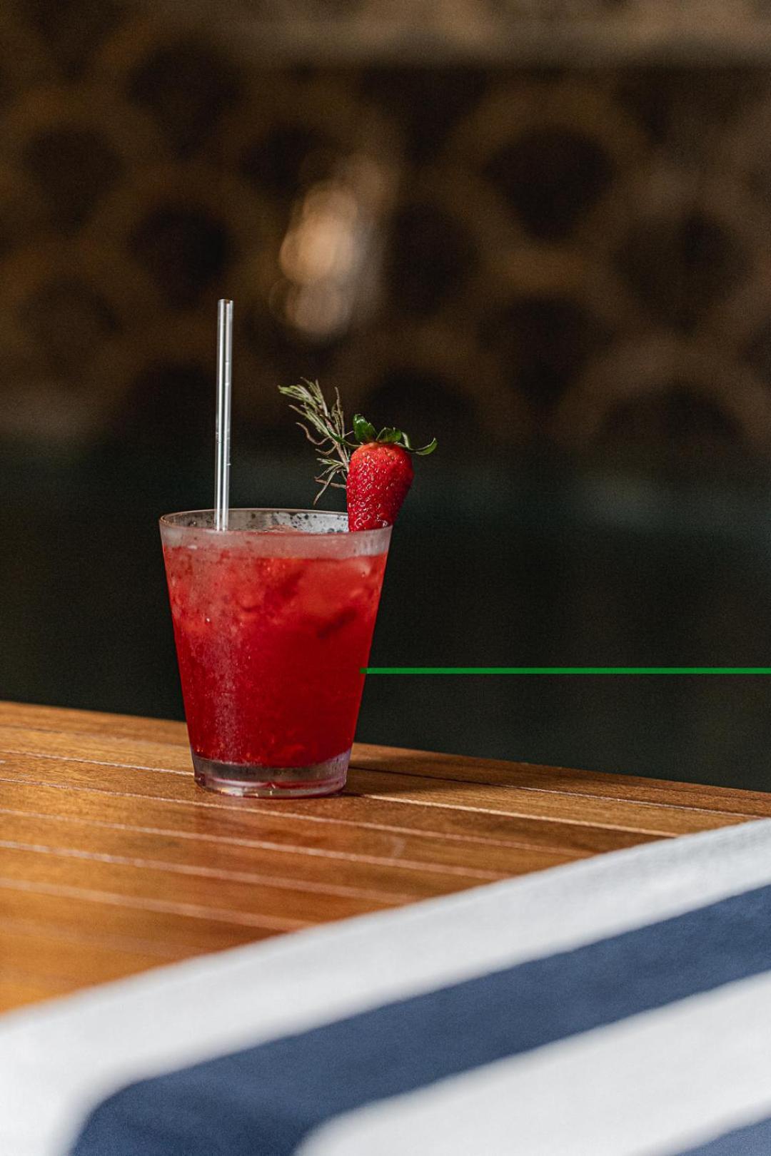 Buona Vitta Gramado Resort & Spa By Gramado Parks Экстерьер фото The photo shows a refreshing cocktail served in a transparent glass. The drink is vibrant red, suggesting it may be made with strawberries or a similar fruit. It features a straw and a garnish of a fresh strawberry on the rim of the glass, along with